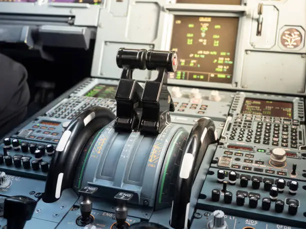 Airbus A320 thrust levers on the centre pedestal instrument panel. Switches and dials visible in the background.