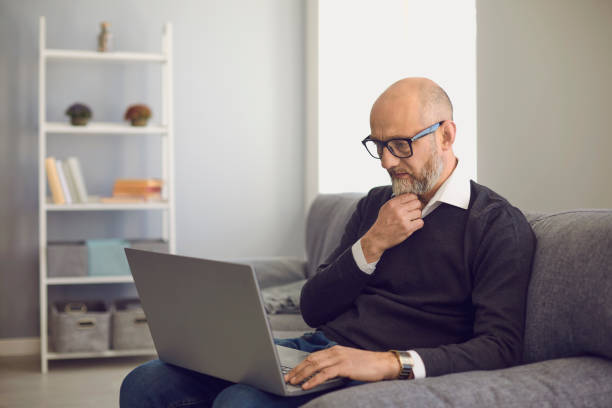 istock Senior man with laptop communicating online, working, consulting doctor or taking educational course at home 1255621445