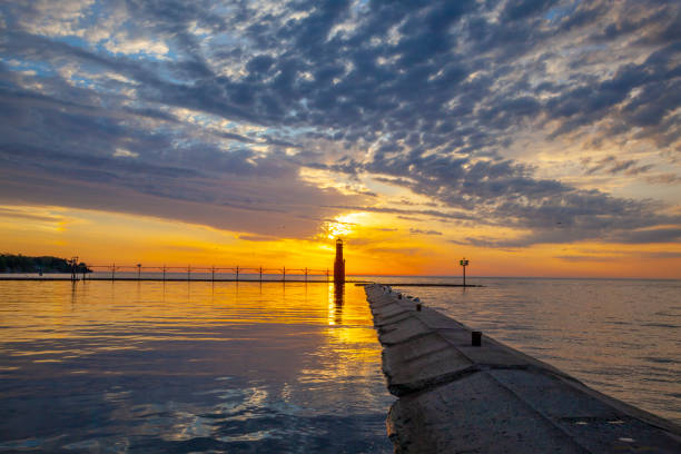 Amazing dawn sky over tranquil harbor with lighthouse on scenic lake.