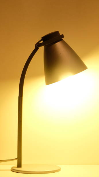 istock Gray desk office lamp is lit with warm yellow light 1255626176