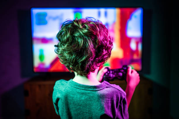 Little boy playing video game Little boy playing video game in the dark room. Focus on the foreground one boy only stock pictures, royalty-free photos & images