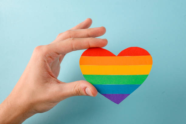 istock Gay holding a rainbow heart on blue background 1255628274