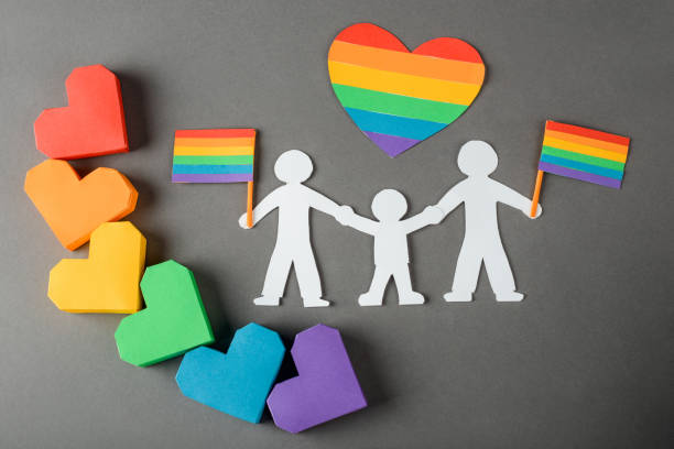 papier homosexuell familie kette und herzen auf grauem hintergrund - lesbian gay man rainbow multi colored stock-fotos und bilder
