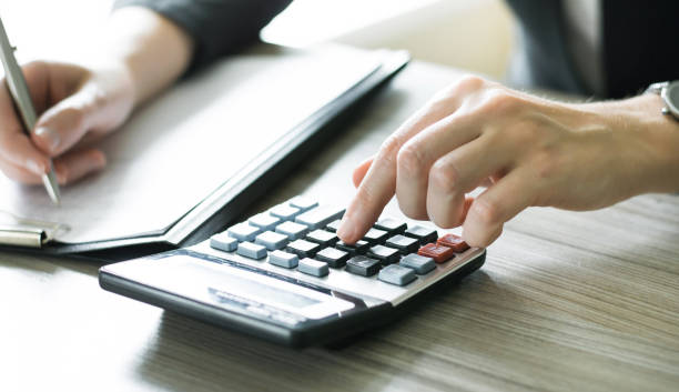 istock accountant working at a table using a calculator to calculate numbers, financial accounting concept. Finance 1255633196