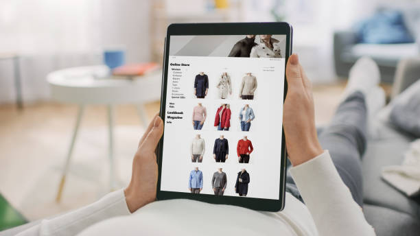 istock Young Woman at Home Laying on a Couch Using Tablet Computer in Horizontal Landscape Mode for Browsing Through Online Retail Shopping Site. Girl is Watching Content, Videos, Blogs. 1255633845