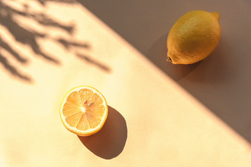 Lemon on yellow background with shadows, top view, flat lay.