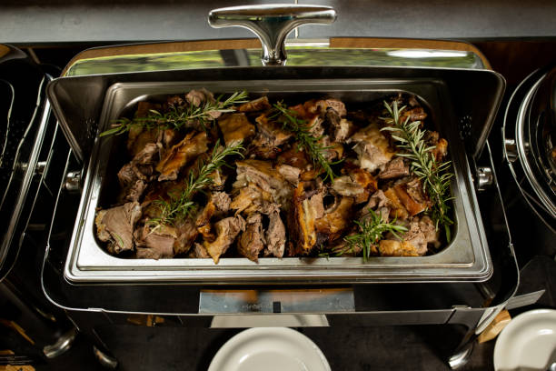 Fresh pork on table with rosemary at chafing dish