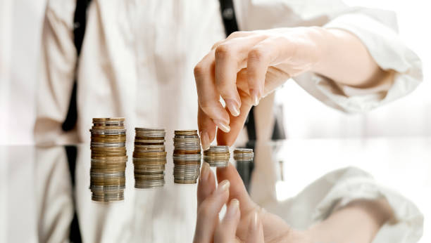 istock Woman stacking coins on mirror table from Smal to big 1255641937