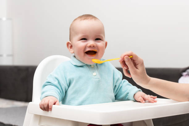 istock Mom Feeds Baby With Fruit Puree At Home 1255651051