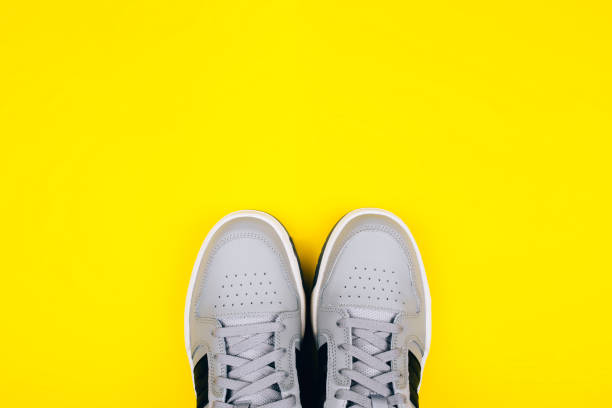 istock Stylish gray sneakers on a yellow background. 1255651150