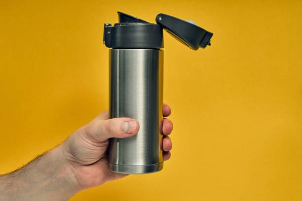 istock Metal mug thermos in hand on a colored background. Hot drinks on the go. Thermo mug. 1255651320