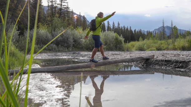 istock Man balances on log and walks across river in the morning 1255651431