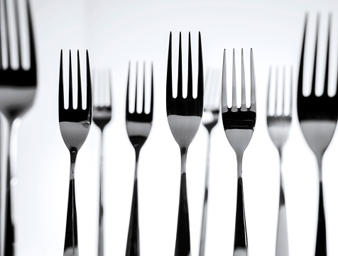 Still life of group of forks standing on white background