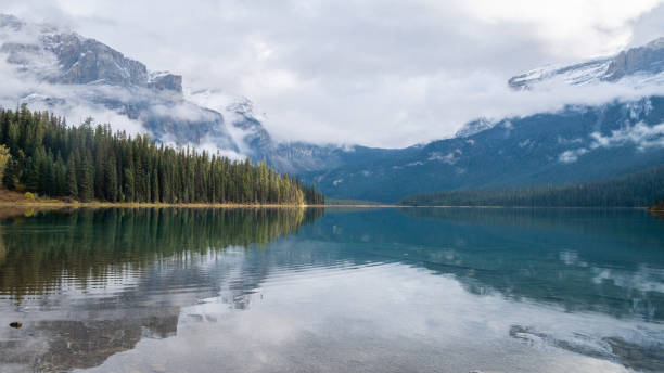 istock Beautiful alpine lake reflecting forest and surrounding mountains 1255657128