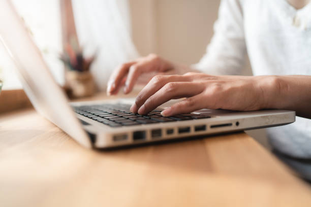 istock Close up hands of woman using laptop computer working and searching online information with blurry background. copy space of technology business and social distancing concept. Bangkok 1255667665