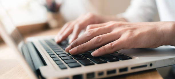 istock Close up hands of woman using laptop computer working and searching online information with blurry background. copy space of technology business and social distancing concept. Panoramic banner portion. Bangkok 1255667666