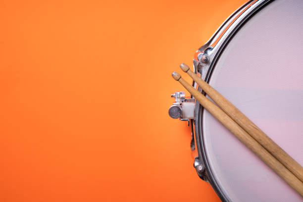 istock Drum stick and drum on orange table background, top view, music concept 1255670603