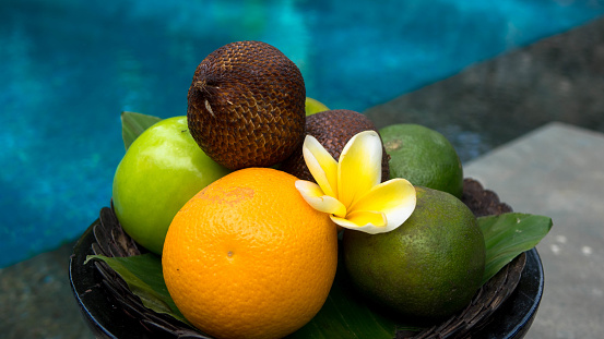 Bowl of different fruits with a swimming pool, Blue swimming pool with colorful fruits, Tropical relaxation in the swimming pool