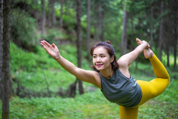 istock Young Asian woman practicing yoga in the forest 1255672658