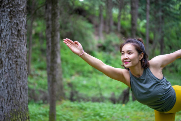 istock Young Asian woman practicing yoga in the forest 1255672720