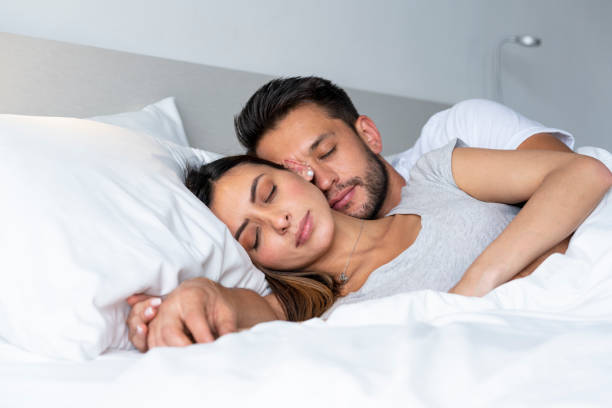 la coppia si abbraccia sdraiata sul loro letto passando la quarantena covid-19 - cold and flu flu virus bed couple foto e immagini stock