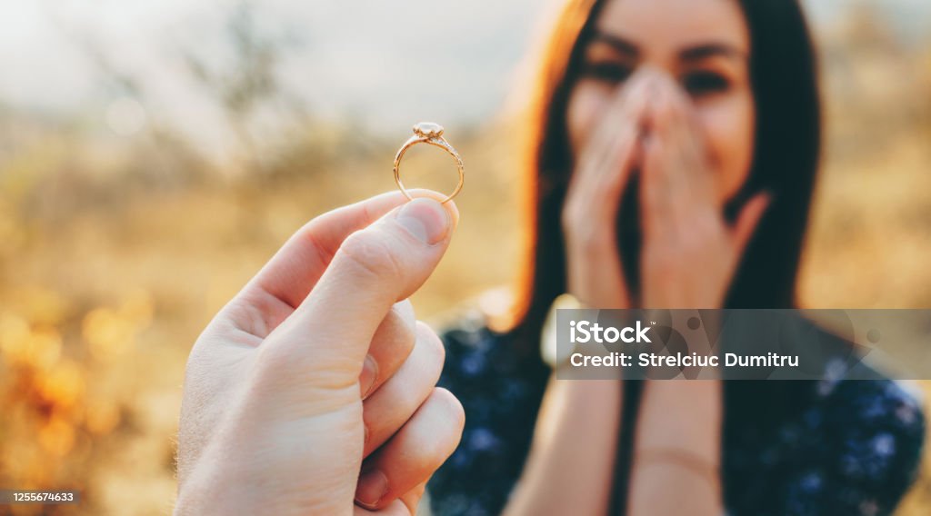 Close up photo of a wedding ring with diamond shown to the girl while she is amazed and covers her face with palms Engagement Stock Photo