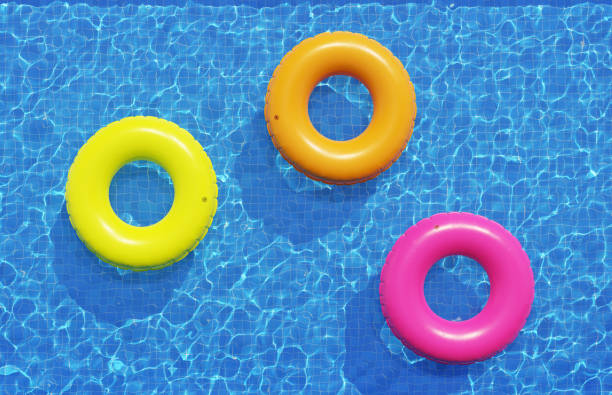 istock Multi-colored swimming rings, floating in blue swimming pool. Top view, 3d illustration 1255683043
