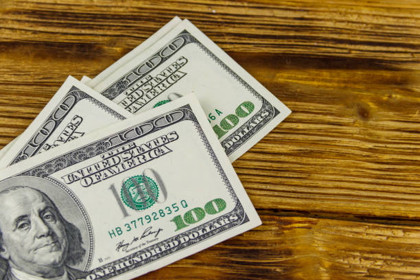 istock Stack of one hundred dollars bills on wooden desk 1255684299