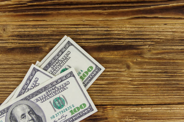 istock Stack of one hundred dollars bills on wooden desk 1255684300