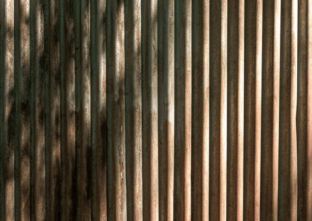istock Old and rusty metal fence lit by sun with shadows. 1255686927