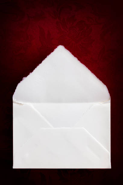 istock Vintage white envelope, top view, over rich red brocade background. 1255689447