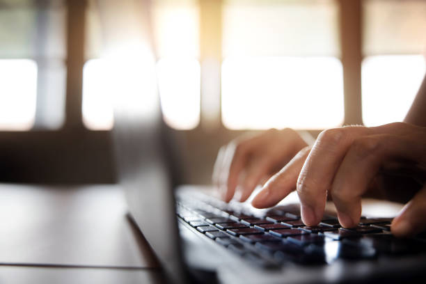 istock Young Woman Typing Computer Laptop Keyboard. Closeup shot and Selective focus on Finger. Working on Desk against Window 1255690552