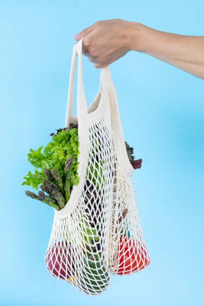 istock Female hand with eco bag on blue background. Zero waste concept 1255692934