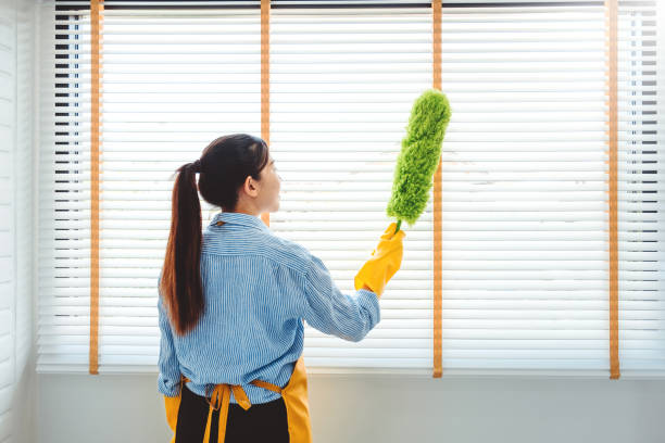 joven mujer asiática limpiando el polvo de limpieza de la casa usando escoba de plumas y plumero mientras limpia en la ventana house mantener el concepto - dust dusting cleaning broom fotografías e imágenes de stock