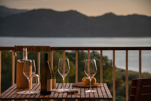 Romantic and informal aperitif setting, over the sea.  Wine bottle and three glasses