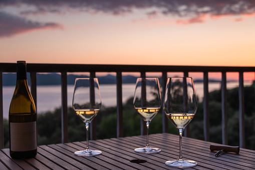Romantic and informal aperitif setting, over the sea.  Wine bottle and three glasses