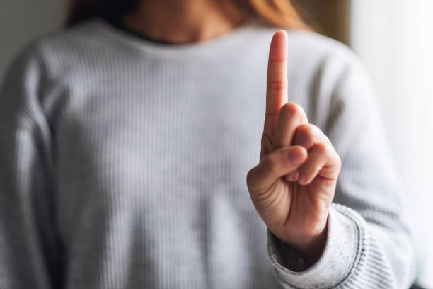 istock a woman making and showing number one hand sign 1255700569