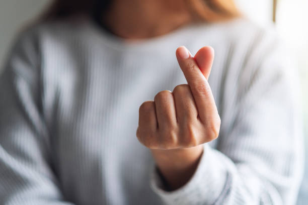 istock a young woman making and showing mini heart hand sign 1255700571
