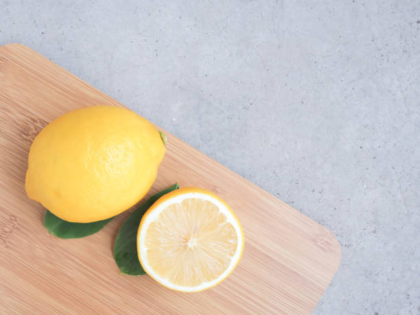 istock Lemon fruit and half on wooden cutting board over grey background. Copy space for text. Top view. 1255702216