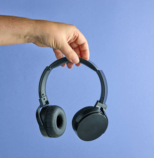 istock Black wireless headphones in human hand 1255702234