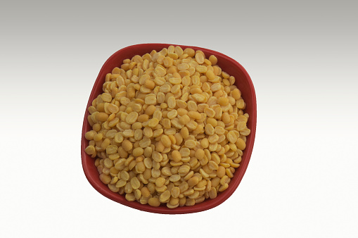 Close up of the yellow Mung Bean (Moong Dal Dhuli) in red bowl grey background New Delhi India.