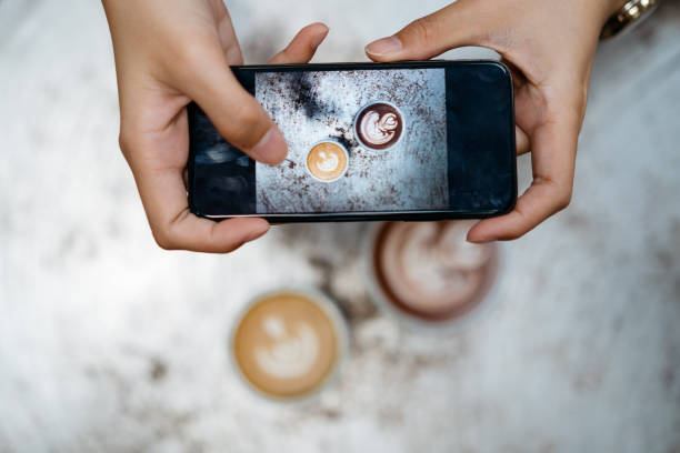 Female photographing coffee latte and hot chocolate with smartphone