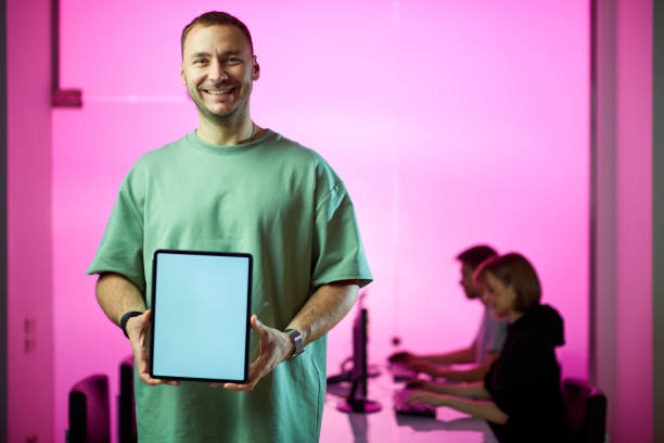 istock Young smiling businessman and his creative design team at the office during developing a new project, pink background 1255710580