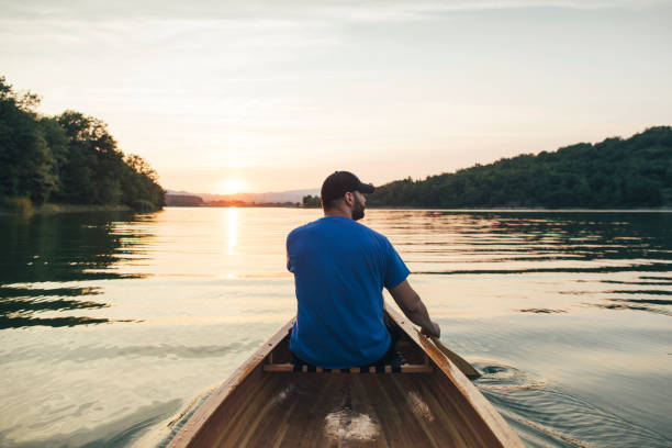istock Rear view of man paddling canoe 1255710596