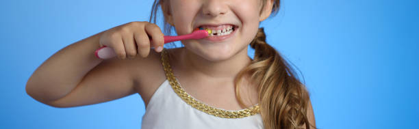 la bambina si sta lavando i denti con uno spazzolino da denti. primo piano. panorama orizzontale - toothpaste glue blue white foto e immagini stock