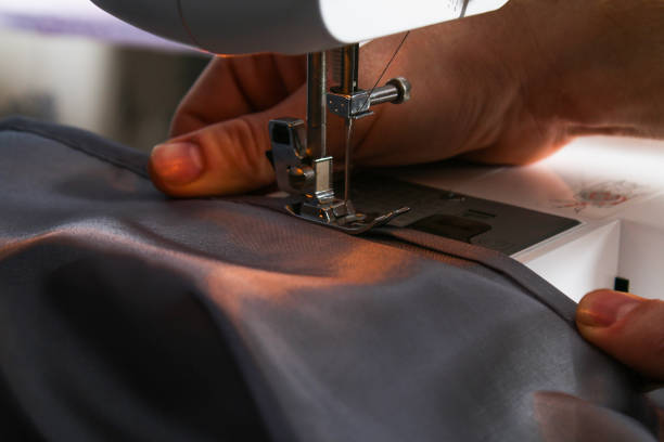 istock A man hem a curtain on a sewing machine. Sewing, hobbies, hobby, home improvement. 1255713866