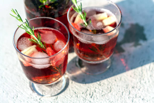 istock Two glasses and carafe with red refreshing summer drink or red wine, ice cube, pieces of watermelon and rosemary sprigs. Summertime concept. Selective focus. 1255715939