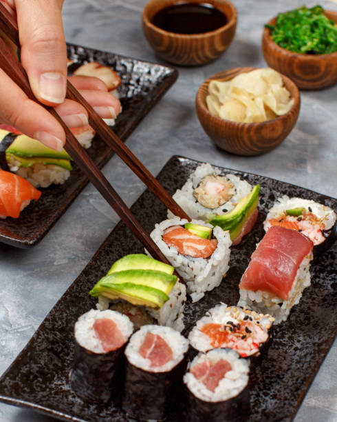 istock Close up of hand taking roll with chopsticks from a plate 1255717138