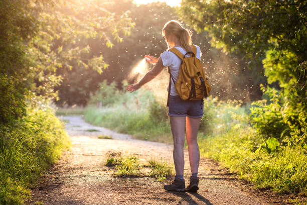 mujer con mochila aplicando repelente de insectos de nuevo mosquito y garrapata al aire libre - insect repellant mosquito bug bite spraying fotografías e imágenes de stock