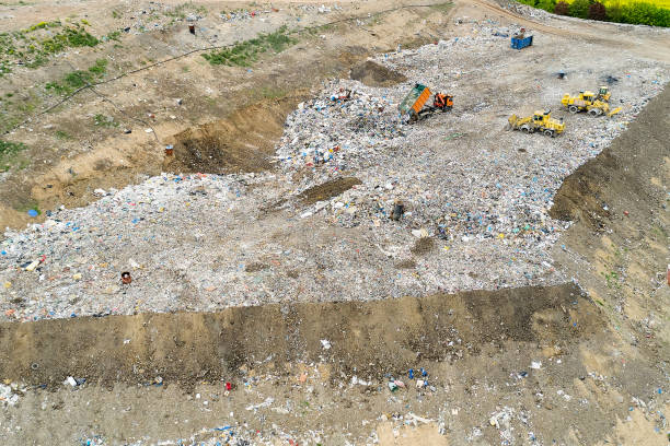 istock Garbage pile in trash dump or landfill. Dump trucks and excavators unloading waste. 1255718279